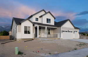 View of front of property with a porch, a garage, and central AC