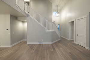 Stairway with a towering ceiling, an inviting chandelier, and hardwood / wood-style floors