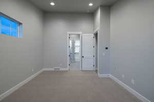 Carpeted empty room featuring a towering ceiling