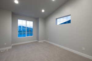 Empty room with carpet, a mountain view, and vaulted ceiling