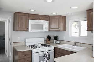 Kitchen with sink, white appliances, new LVP flooring.