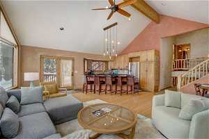 Living room featuring high vaulted ceiling, light hardwood / wood-style flooring, beam ceiling, and ceiling fan