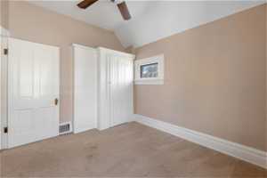 Unfurnished bedroom featuring lofted ceiling, carpet floors, and ceiling fan with built in cabinetry