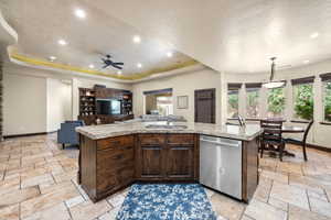 Kitchen with sink, dishwasher, an island with sink, and a raised ceiling