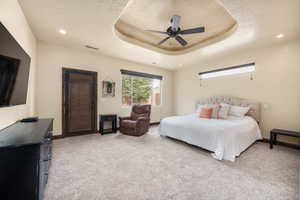 Carpeted bedroom with ceiling fan and a tray ceiling