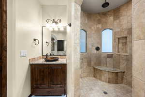 Bathroom featuring tiled shower and vanity with extensive cabinet space