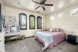 Carpeted bedroom with multiple windows and ceiling fan