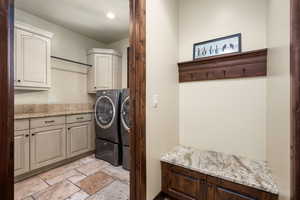 Laundry room with cabinets, independent washer and dryer, and light tile floors