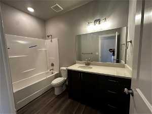 Full bathroom with tub / shower combination, toilet, hardwood / wood-style floors, and large vanity
