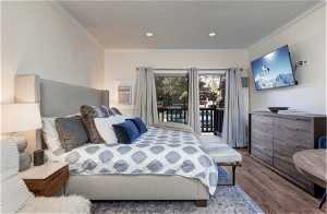 Bedroom with hardwood / wood-style flooring, access to exterior, and ornamental molding
