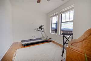 Exercise room with hardwood / wood-style floors and ceiling fan
