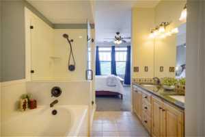 Bathroom with dual bowl vanity, tile flooring, ceiling fan, and a tub