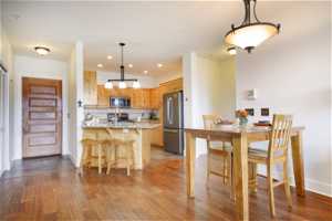 Kitchen with backsplash, stainless steel appliances, hardwood / wood-style flooring, and hanging light fixtures