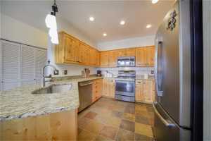 Kitchen with light stone counters, sink, dark tile flooring, tasteful backsplash, and stainless steel appliances