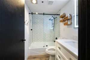 Full bathroom featuring LVP flooring, vanity, toilet, and tiled shower / bath