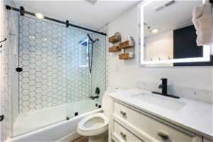 Full bathroom with toilet, vanity, and shower / bath combination with glass door
