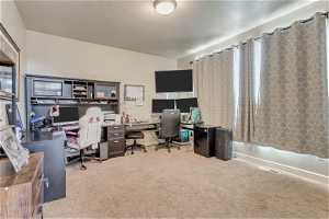 Home office with a textured ceiling and light carpet