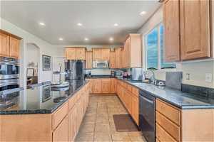 Kitchen featuring sink, appliances with stainless steel finishes, light tile floors, and a kitchen island