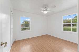 Spare room featuring a wealth of natural light, light hardwood / wood-style floors, and ceiling fan