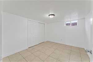 Empty room with a textured ceiling and light tile floors