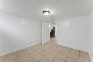 Empty room featuring light tile floors and a textured ceiling