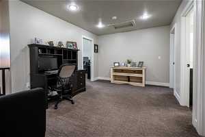 Office space featuring a textured ceiling and dark carpet