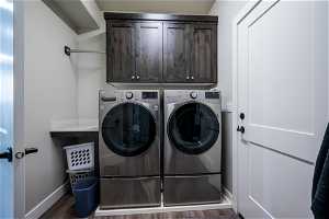 Laundry area featuring independent washer and dryer, dark hardwood / wood-style flooring, and cabinets