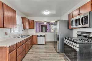 Kitchen with light hardwood / wood-style flooring, stainless steel appliances, ceiling fan, and sink