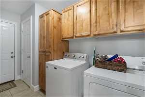 Clothes washing area featuring independent washer and dryer, cabinets, and light tile floors