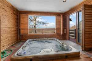 Miscellaneous room featuring a wealth of natural light, wood walls, and a hot tub