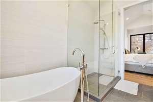 Bathroom with vaulted ceiling, tile floors, and separate shower and tub