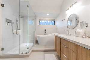Bathroom with vanity, shower with separate bathtub, tile floors, and tile walls