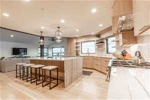 Kitchen with hanging light fixtures, light hardwood / wood-style flooring, plenty of natural light, and light brown cabinets