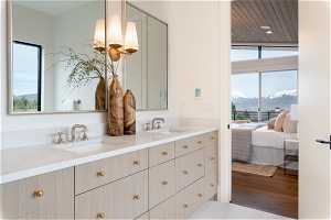 Bathroom with a mountain view, dual vanity, lofted ceiling, wood-type flooring, and an inviting chandelier