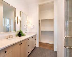 Bathroom featuring dual sinks, oversized vanity, a shower with shower door, and tile flooring