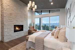 Bedroom featuring a mountain view, a fireplace, a high ceiling, hardwood / wood-style floors, and a notable chandelier