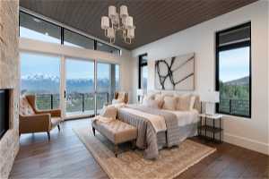 Bedroom with a mountain view, access to exterior, wooden ceiling, hardwood / wood-style flooring, and an inviting chandelier