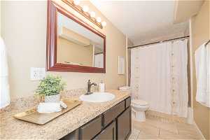 Full bathroom with shower / bath combination with curtain, toilet, tile flooring, a textured ceiling, and vanity