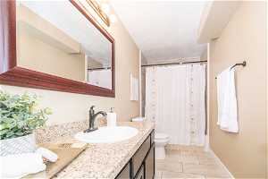 Full bathroom featuring toilet, tile flooring, vanity, and shower / bath combination with curtain