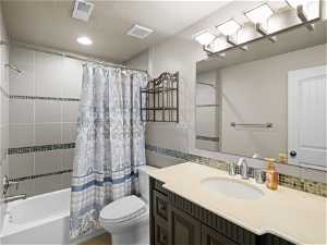 Full bathroom with shower / tub combo, toilet, large vanity, and a textured ceiling