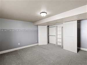 Unfurnished bedroom with a closet, a textured ceiling, and carpet
