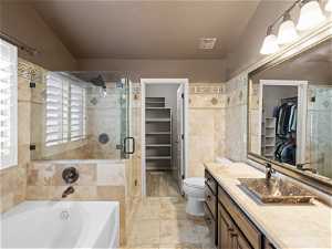 Master bathroom with tile walls, toilet, vanity with extensive cabinet space, tile flooring, and plus walk in shower