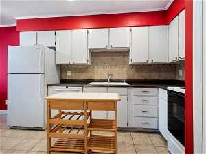 Kitchen with white cabinetry, tasteful backsplash, and white appliances