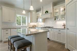 Kitchen with white cabinets, light hardwood / wood-style flooring, tasteful backsplash, and a kitchen island