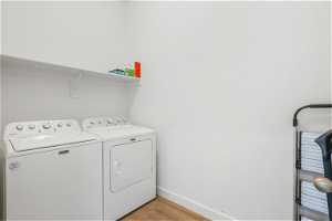 Laundry room with separate washer and dryer and light hardwood / wood-style floors