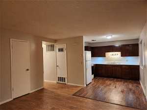 Kitchen featuring white refrigerator, sink, dark hardwood / wood-style floors, and dark brown cabinetry