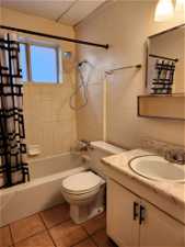 Full bathroom with vanity with cabinet space, shower / tub combo, toilet, and tile floors