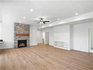 Unfurnished living room featuring light hardwood / wood-style floors, ceiling fan, and a fireplace