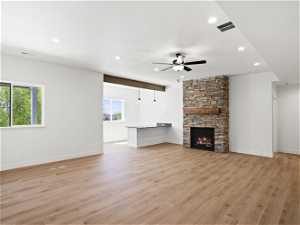 Unfurnished living room featuring light hardwood / wood-style flooring, ceiling fan, and a fireplace