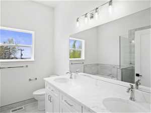 Bathroom featuring dual bowl vanity, toilet, tile floors, and a bathtub